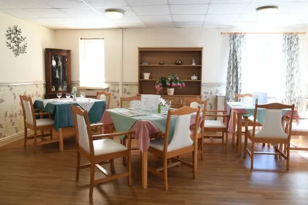 A bright dining room with tables laid for lunch