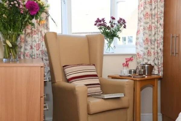 A cosy armchair beside a window with flowers