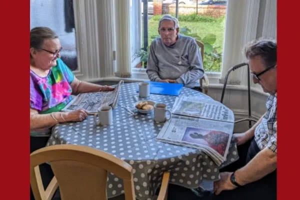 Residents chatting over the morning papers at a table