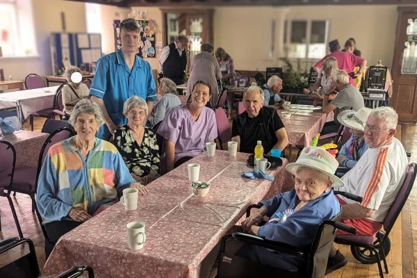 Residents and staff gathered around a table for tea and conversation